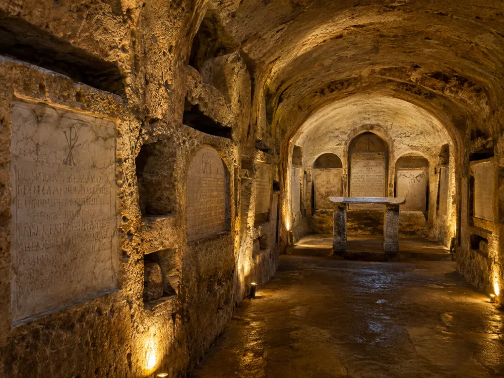 A burial chamber of the kind the Crypt of the Popes occupies, inscribed marble set into the wall